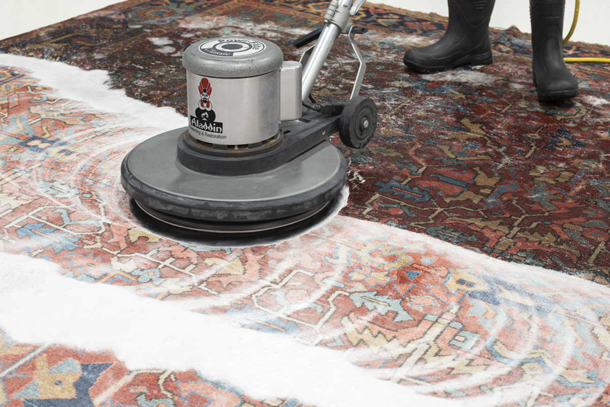An oriental rug is thoroughly saturated with water and cleaned with powerful scrubbing equipment
