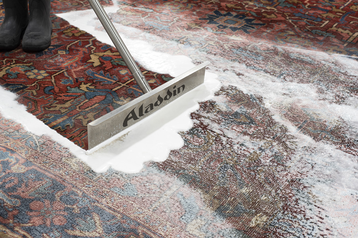 Professional cleaning shampoos are worked into oriental rug with single blade rubber squeegee