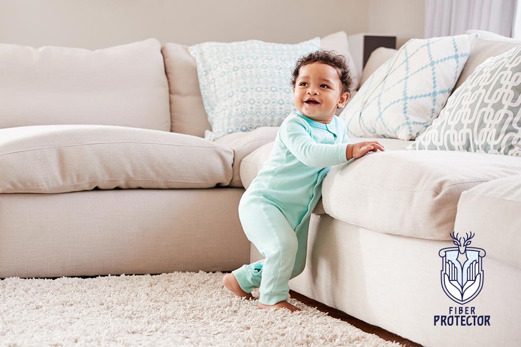 A baby standing against a white couch that's been professionally cleaned and fabric protection applied